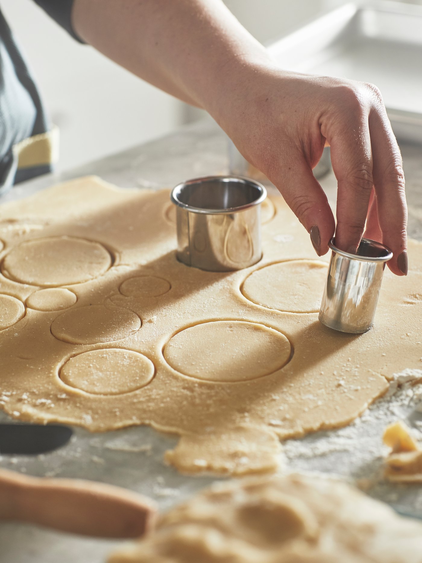 Someone is cutting cookies from dough using a silver‑coloured LÄTTBAKAD cookie cutter.