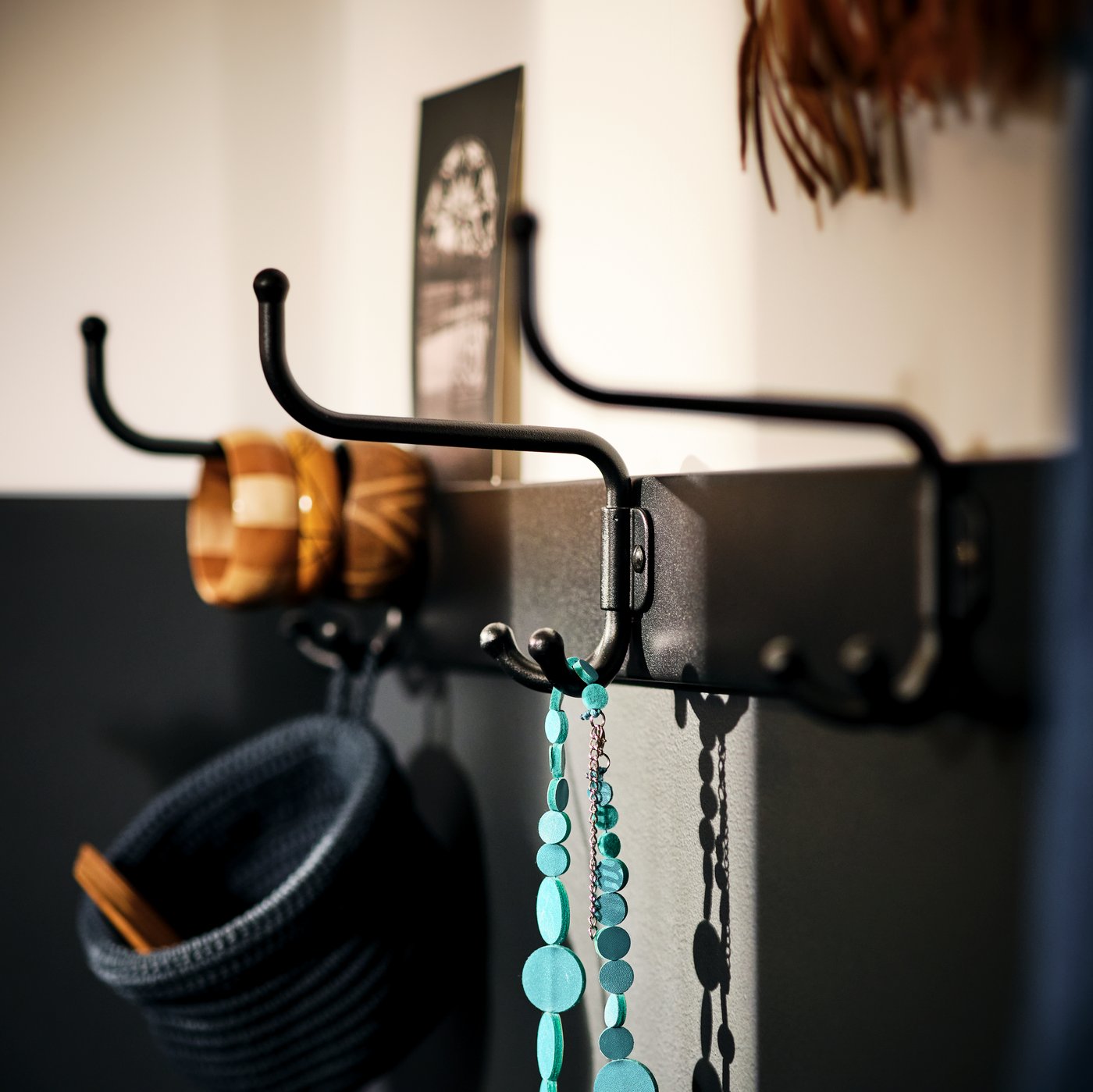 Close-up of the NEREBY rail, made of birch wood, with white NEREBY hooks hanging from it.