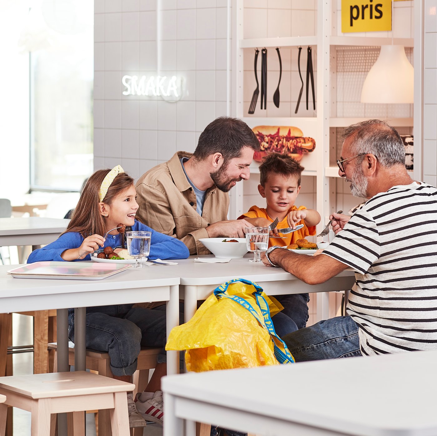 Group dining together at a bright café table with trays of food, water glasses and modern décor in the background.