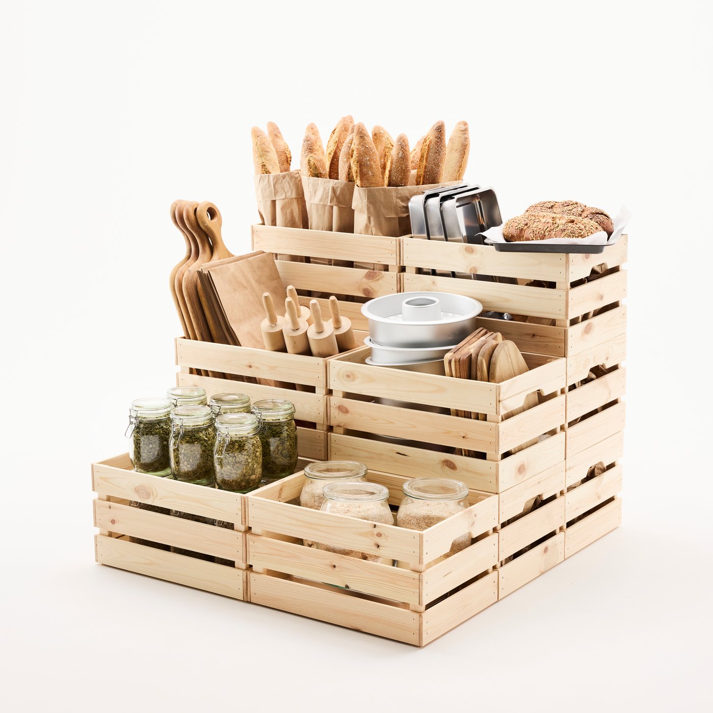 Several KNAGGLIG boxes in solid wood, stacked in three layers and filled with bakeware, ingredients, and freshly baked bread.