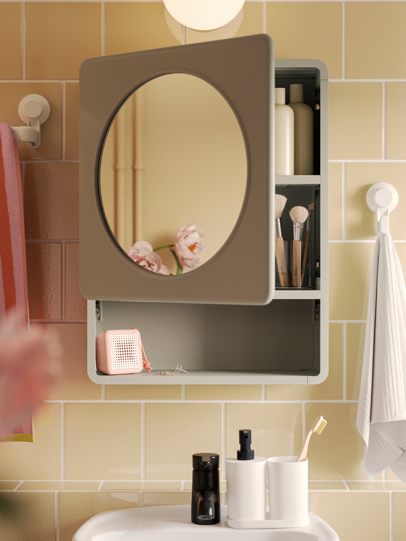 A green IVÖSJÖN mirror cabinet with a door and a shelf is mounted on a yellow-tiled wall above a SKATSJÖN single wash-basin.