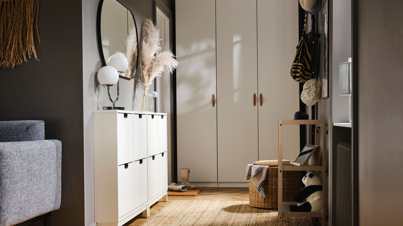 Behind a bed is a dark grey PAX/MEHAMN wardrobe with the left sliding door slightly open, showing clothes hanging on a rail.