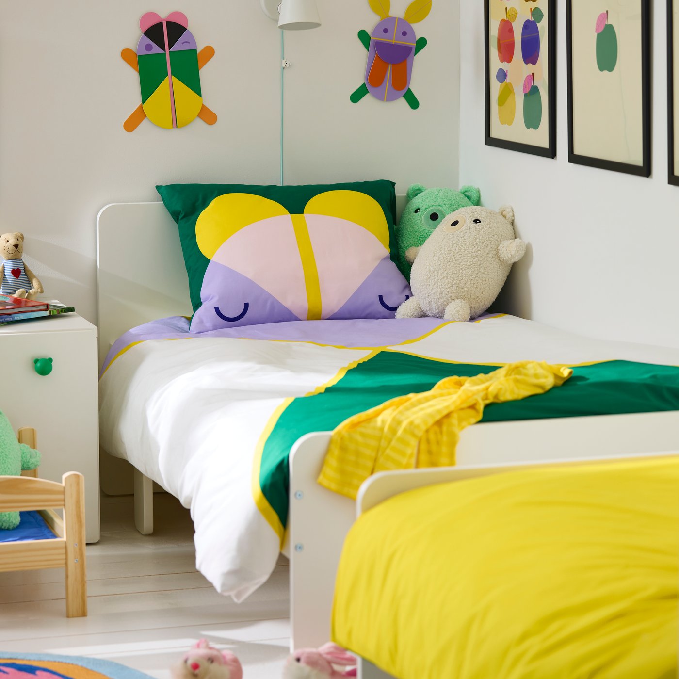 GRESIMOJS wall decoration hang above a child’s bed dressed with GRESIMOJS bedding. Two GRESIMOJS soft toys are on the bed.