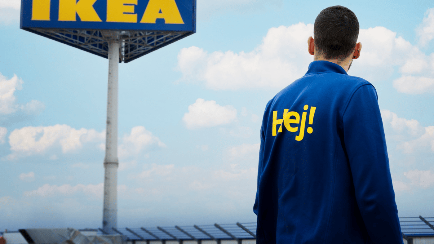 IKEA Co-worker stands in front of IKEA sign.