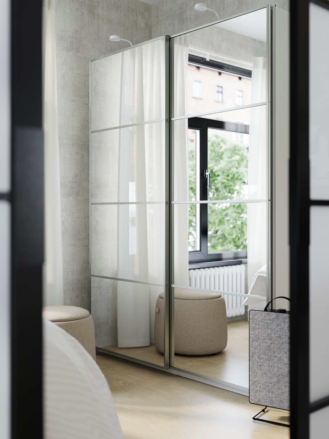 A window and sheer curtains are reflected in the closed, mirror glass sliding doors of a PAX/AULI wardobe on a bedroom wall.