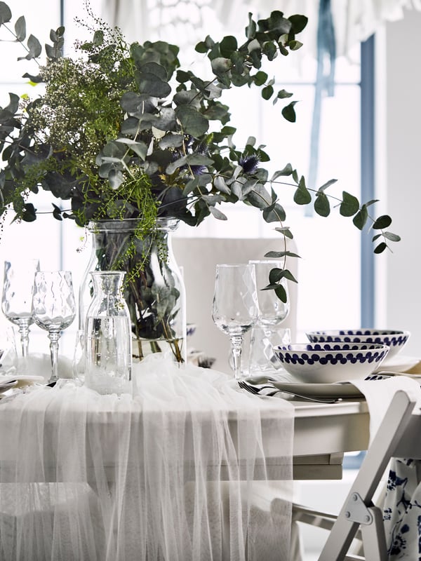 Una mesa de boda con un gran centro de mesa de hojas de eucalipto