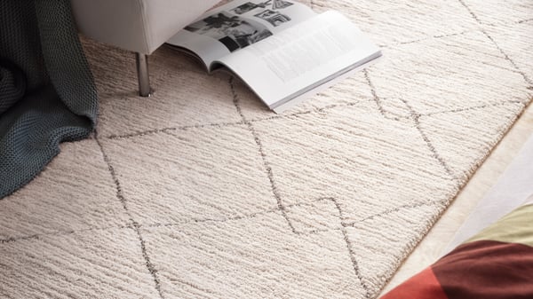 A beige TVERSTED rug, low pile in the bedroom.