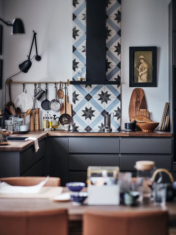A modern kitchen with VOXTORP fronts in dark grey, with a wooden worktop and a kitchen tile backsplash.