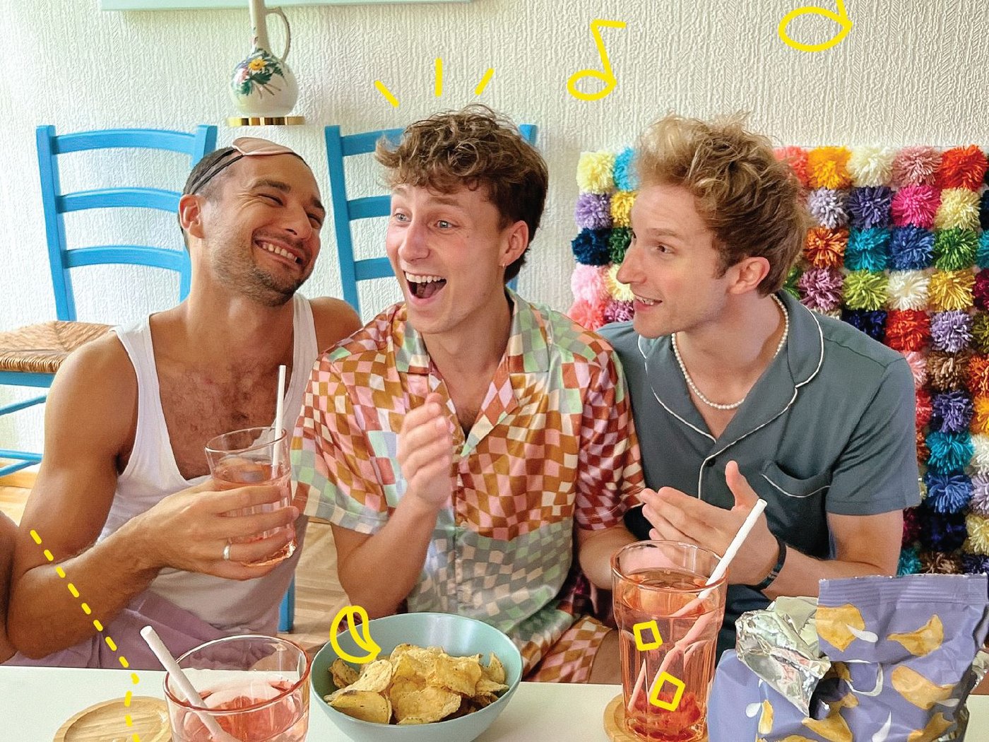 Eine Gruppe junger Menschen sitzt rund um einen Couchtisch, auf dem Getränke und Snacks stehen.