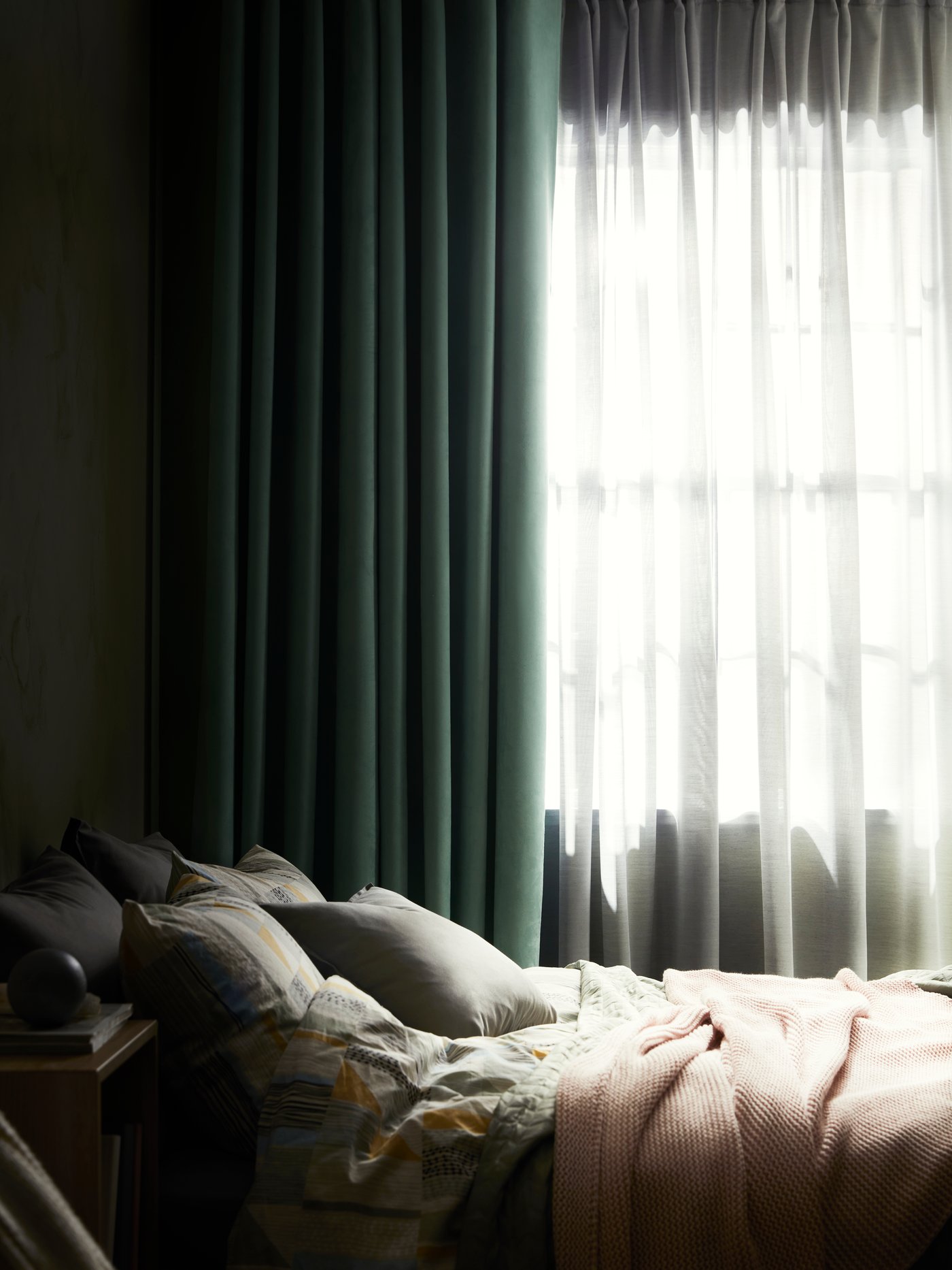 A bed stands near a window with a window treatment consisting of BIRTNA block-out curtains and HILJA curtains.