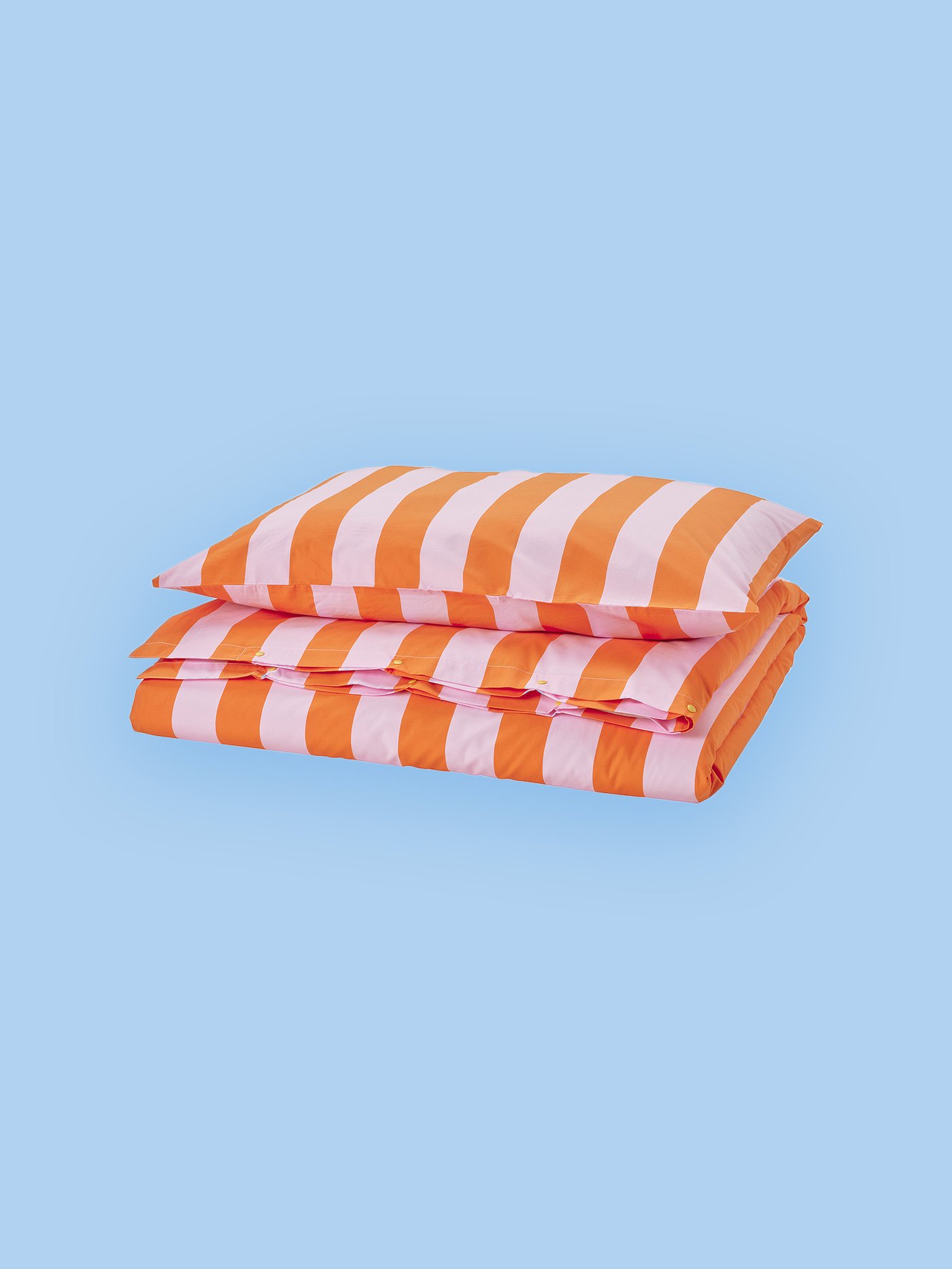 An image of a pillow and a quilt in stretched colors orange and pink against a blue background.