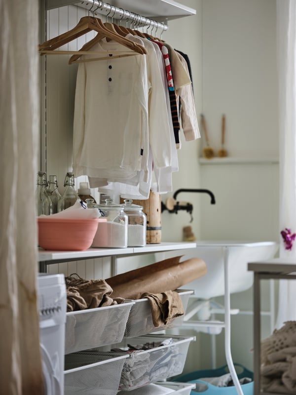 Espace buanderie avec combinaison de rangement BOAXEL en blanc accueillant des vêtements sur cintre, des accessoires de lessive, etc.