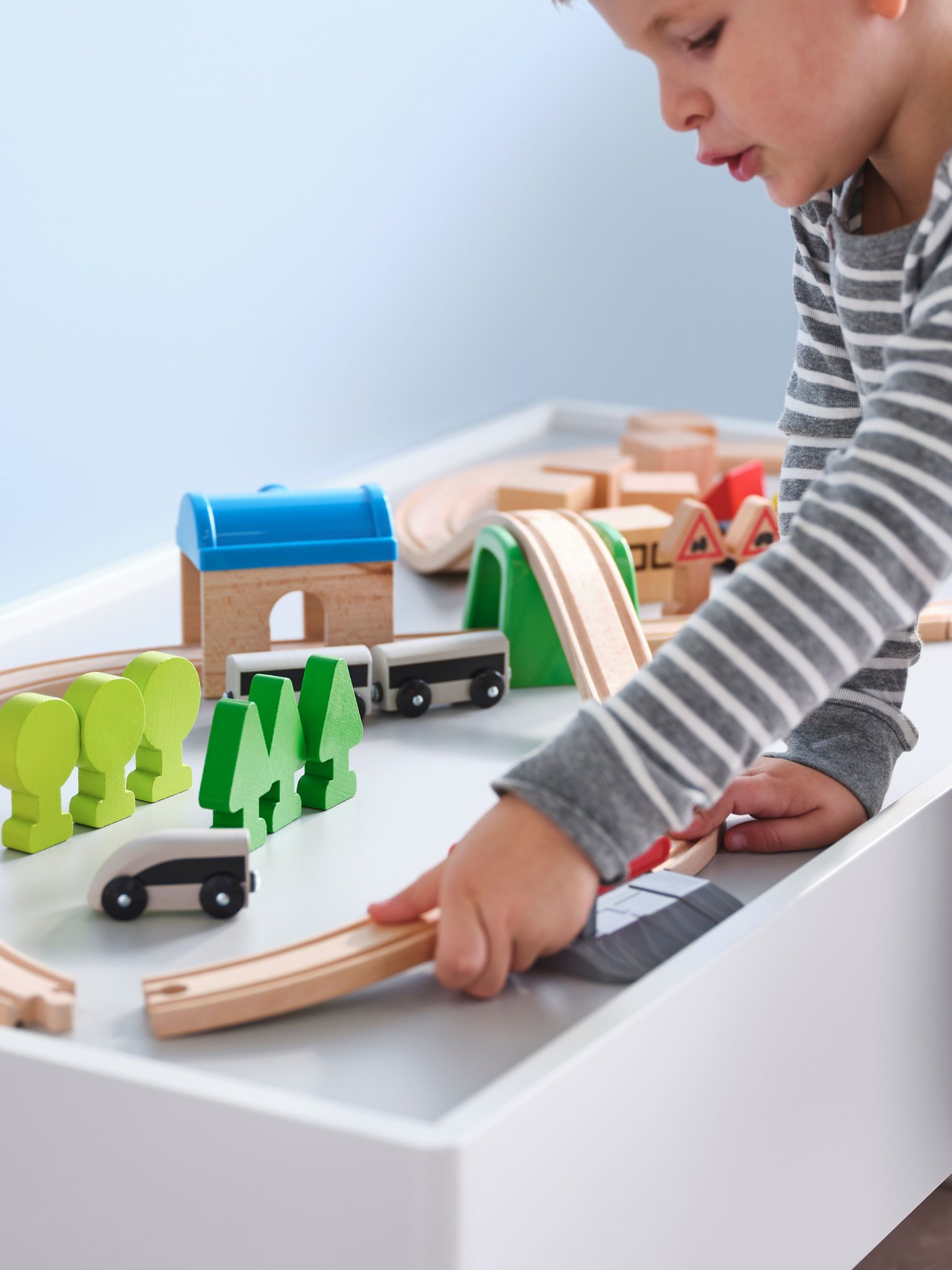 Una niña jugando con una pista de trenes de madera de la serie LILLABO.