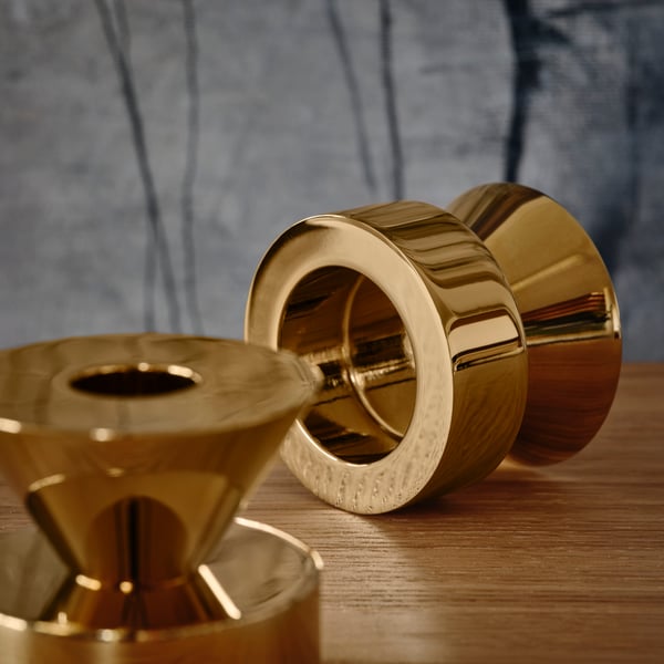 Two STOCKHOLM 2025 candlestick/tealight holders on a wooden surface. One of them is lying on its side, showing the underside.