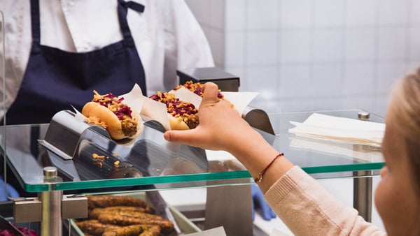 A child reaching for a hot dog at the IKEA Bistro