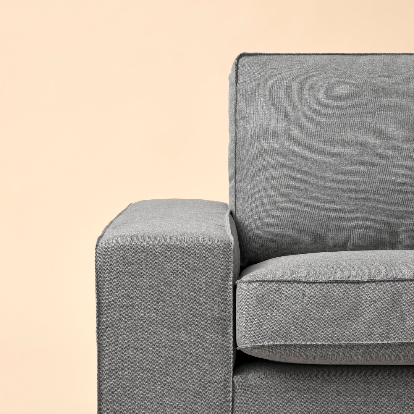 Part of a KIVIK three-seat sofa in a Tibbleby beige-grey fabric placed against a pale-yellow background.