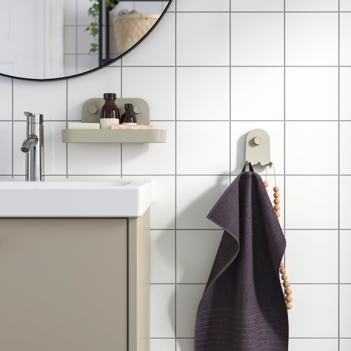 An ÖBONÄS triple hook with suction cup on a white-tiled bathroom wall, with a grey towel and wooden beads hanging from it.