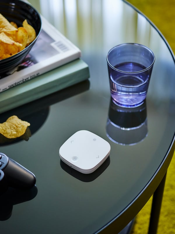 IKEA Home smart daljinski upravljač STYRBAR nalazi se na FRÖTORP staklenom stolu.