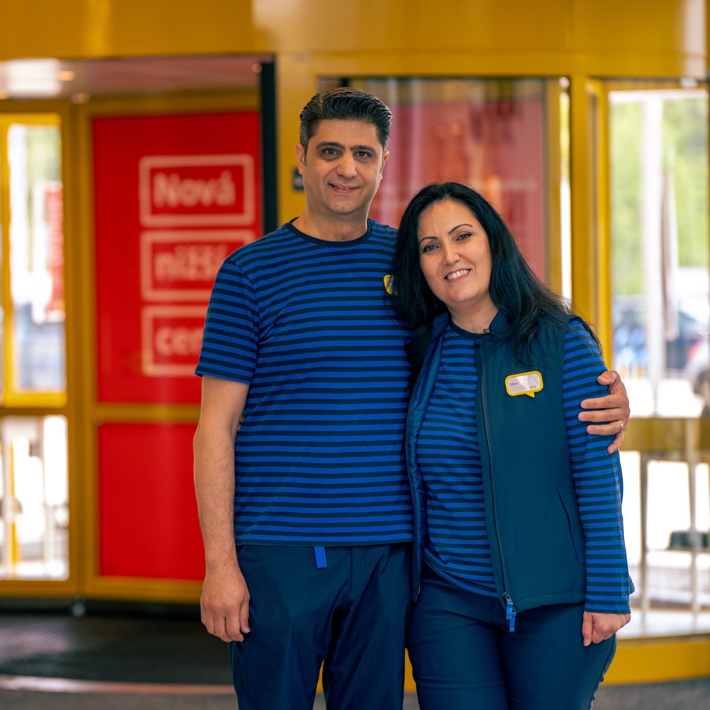 Zagrljeni Silva i Abdul u plavim IKEA radnim uniformama.