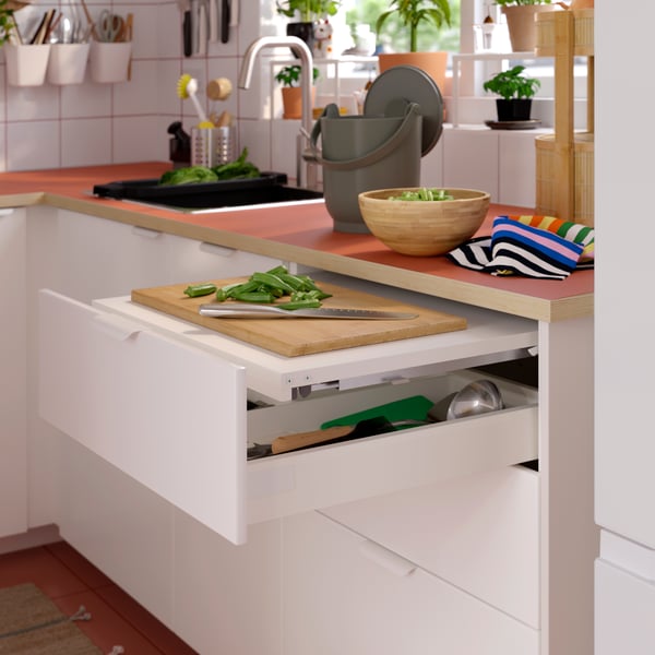 Various kitchen items standing on an EKBACKEN worktop and METOD/MAXIMERA pull-out work surfaces and storage, cutlery inside.