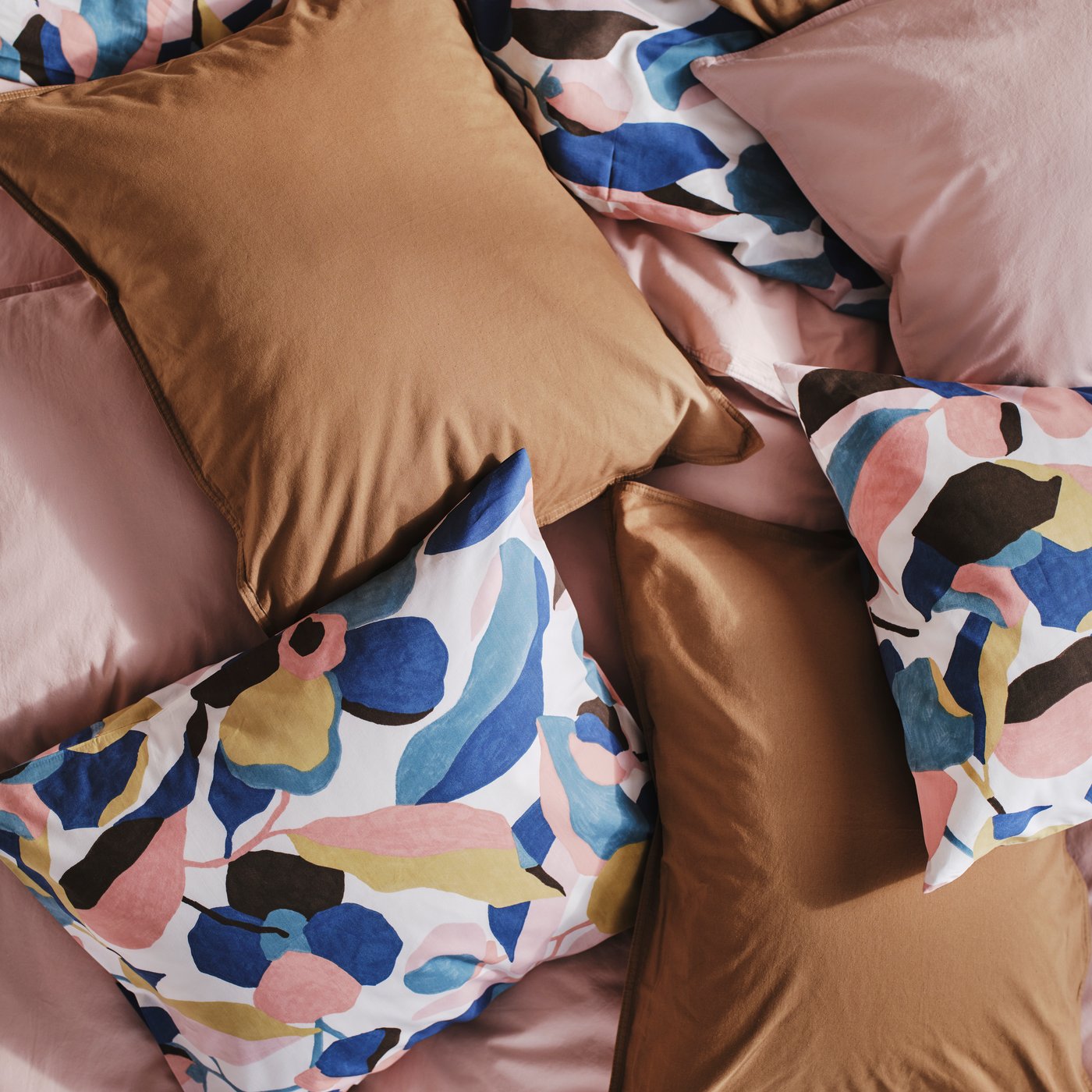 ÄNGSLILJA bed linen in light brown and pink are scattered on a bed together with VIDEOXBÄR duvet cover and pillowcases.