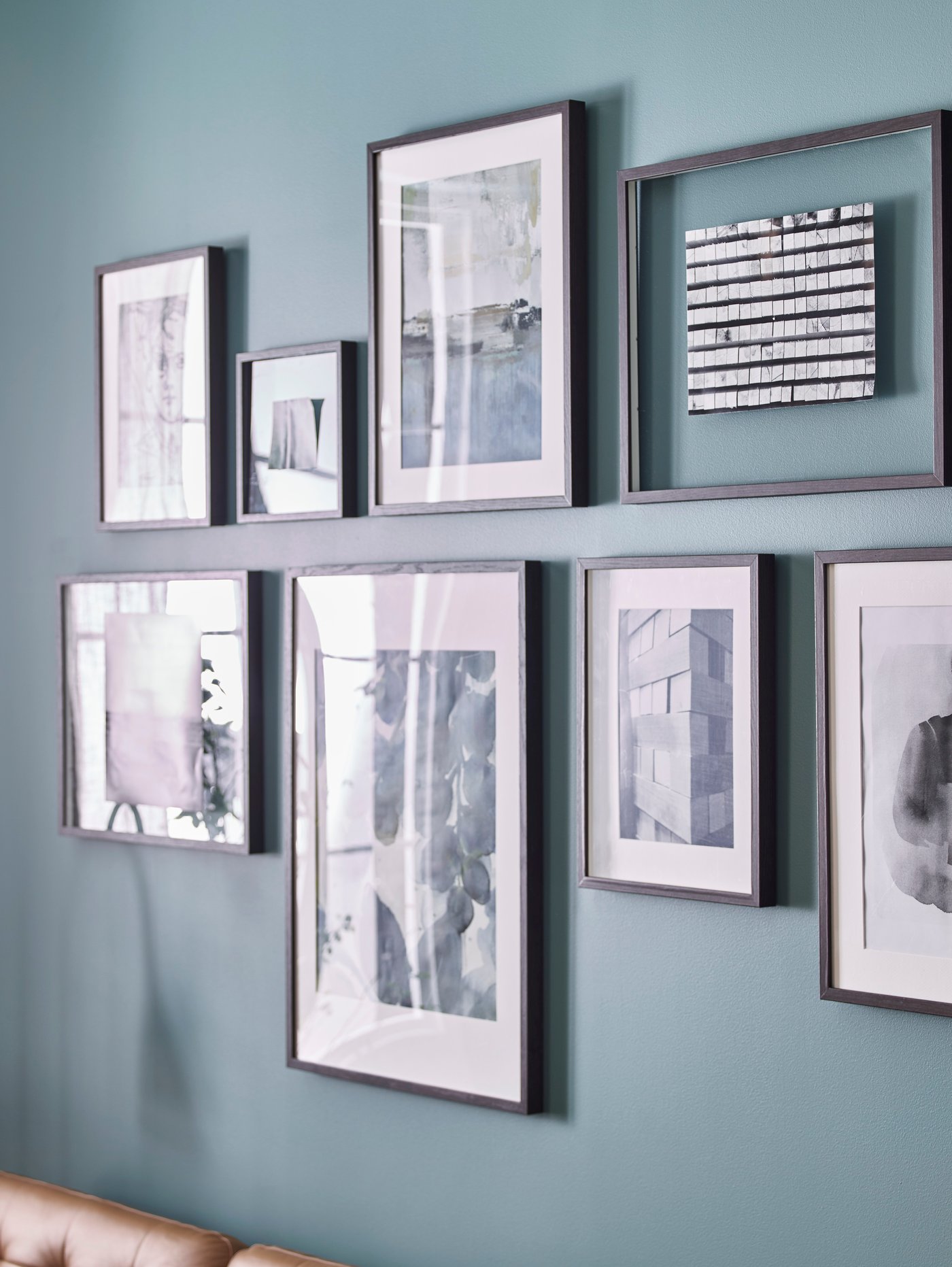 IKEA HOVSTA plastic black picture frames in different shape and sizes, arranged on a wall.