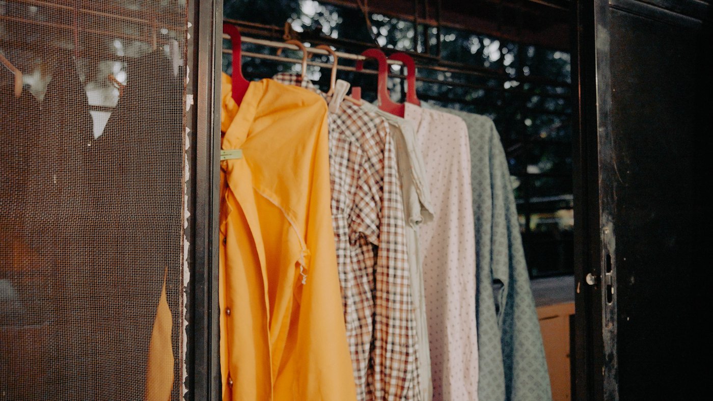 Clothes in different colors and shapes hanging on a rope gainst the the wire yard background.