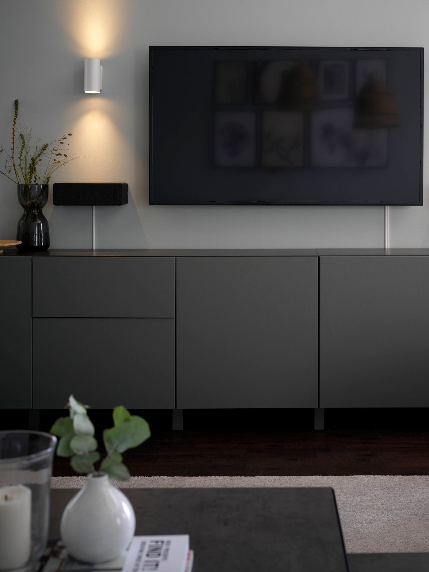 A grey BESTA storage solution under a wall-mount TV 