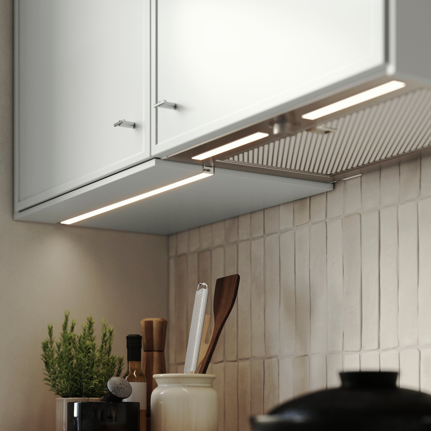 A kitchen with MITTLED LED kitchen worktop lighting strip under light grey cabinets, shining onto tiled wall and worktop.