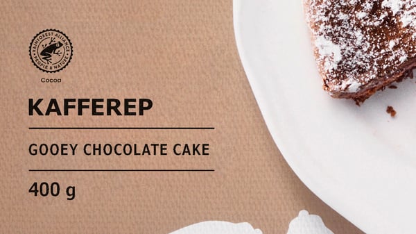 Pakovanje KAFFEREP torte s topljenom čokoladom na kom se vidi parče torte na belom tanjiru i Rainforest Alliance logotip s kakaoom.