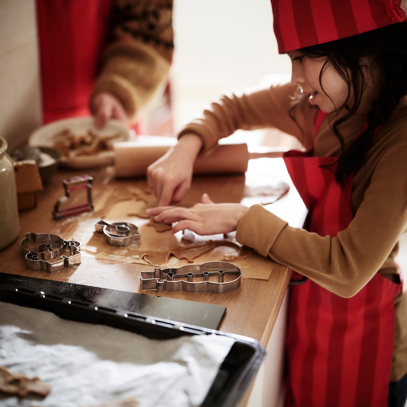 A child cutting out festive cookies from a sheet of dough using VINTERFINT pastry cutters.