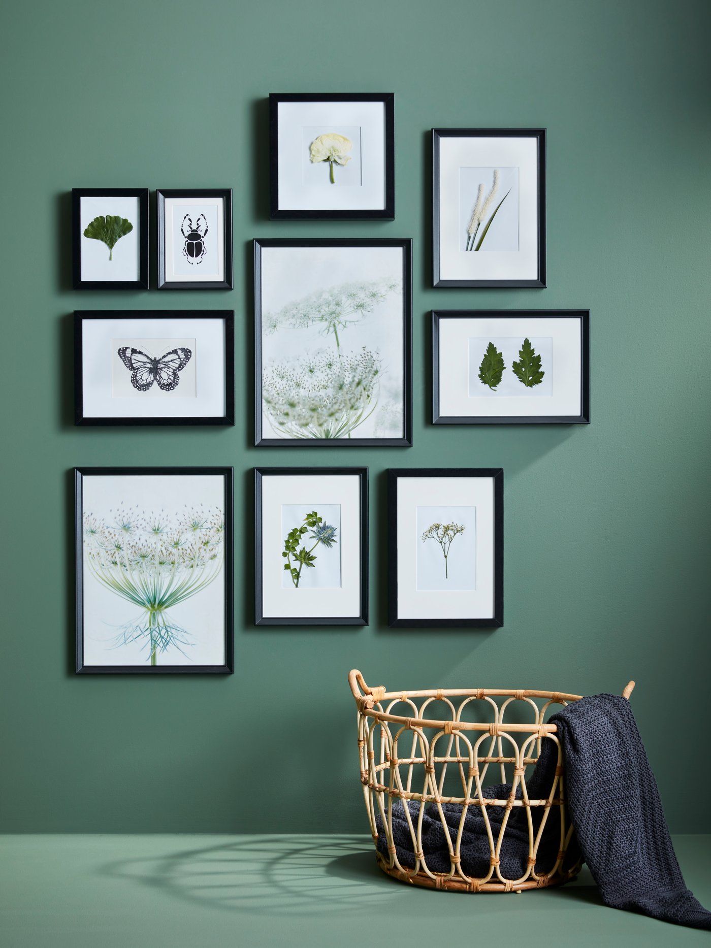 Various sizes of black FISKBO photo frames on a green wall.