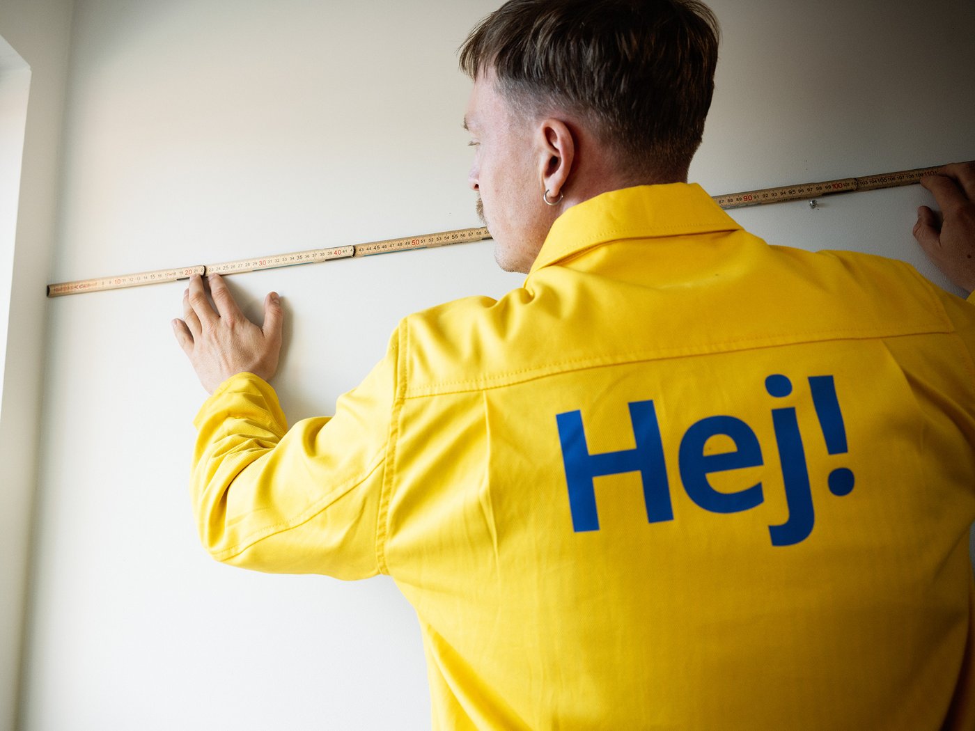 Ein IKEA Mitarbeiter hölt ein Maßband an eine Wand