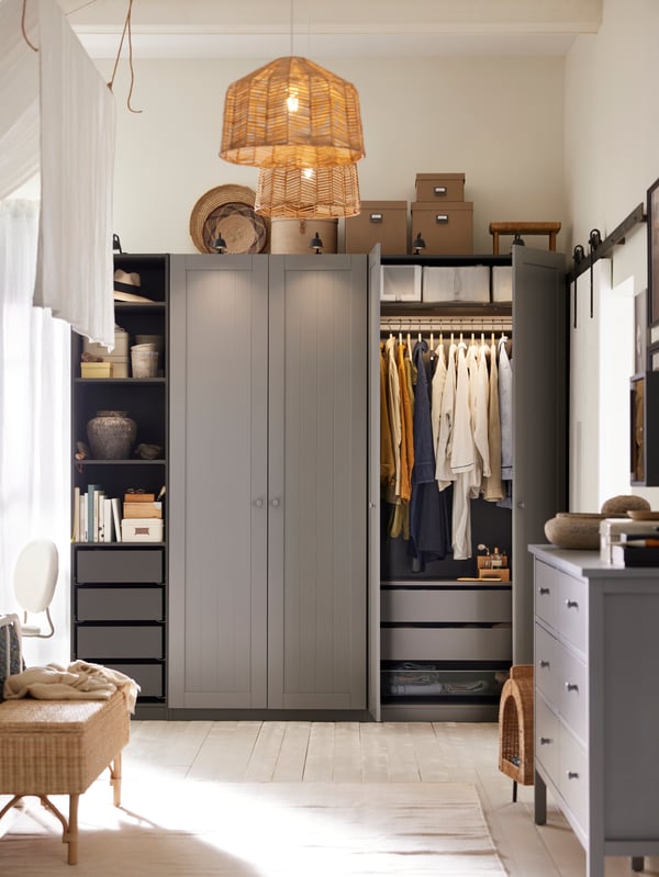 Un agencement d’armoire-penderie PAX/GULLABERG gris foncé/gris dont deux portes sont ouvertes, montrant des vêtements sur un rail et des boîtes à chaussures sur une tablette.