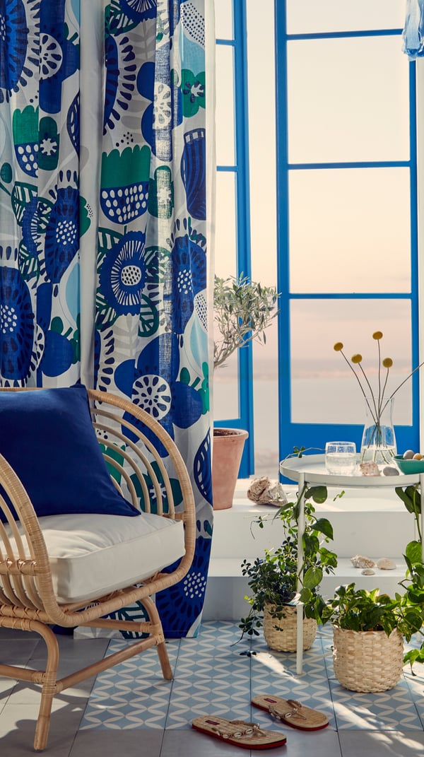 Habitación con silla, plantas y cortinas.