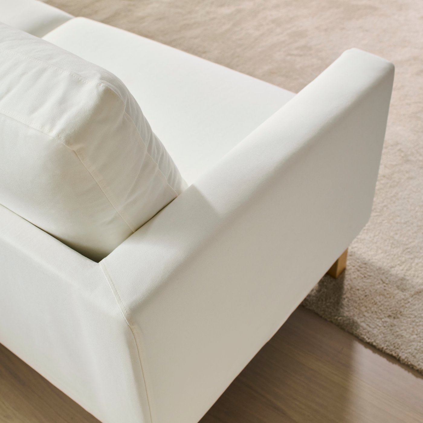 En hvid SALTSJÖBADEN 2-personers sofa, der står med forbenene på et tæppe i en lys stue.