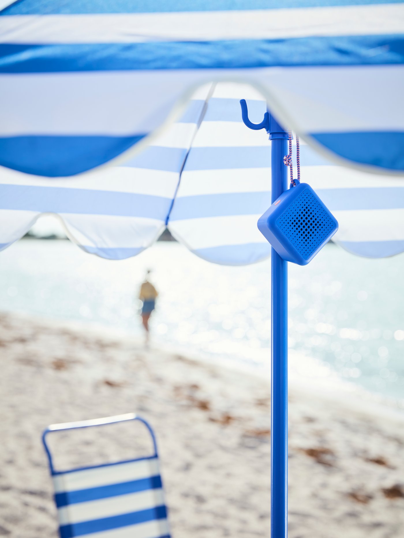 Enceinte Bluetooth VAPPEBY suspendue à un parasol sur la plage.