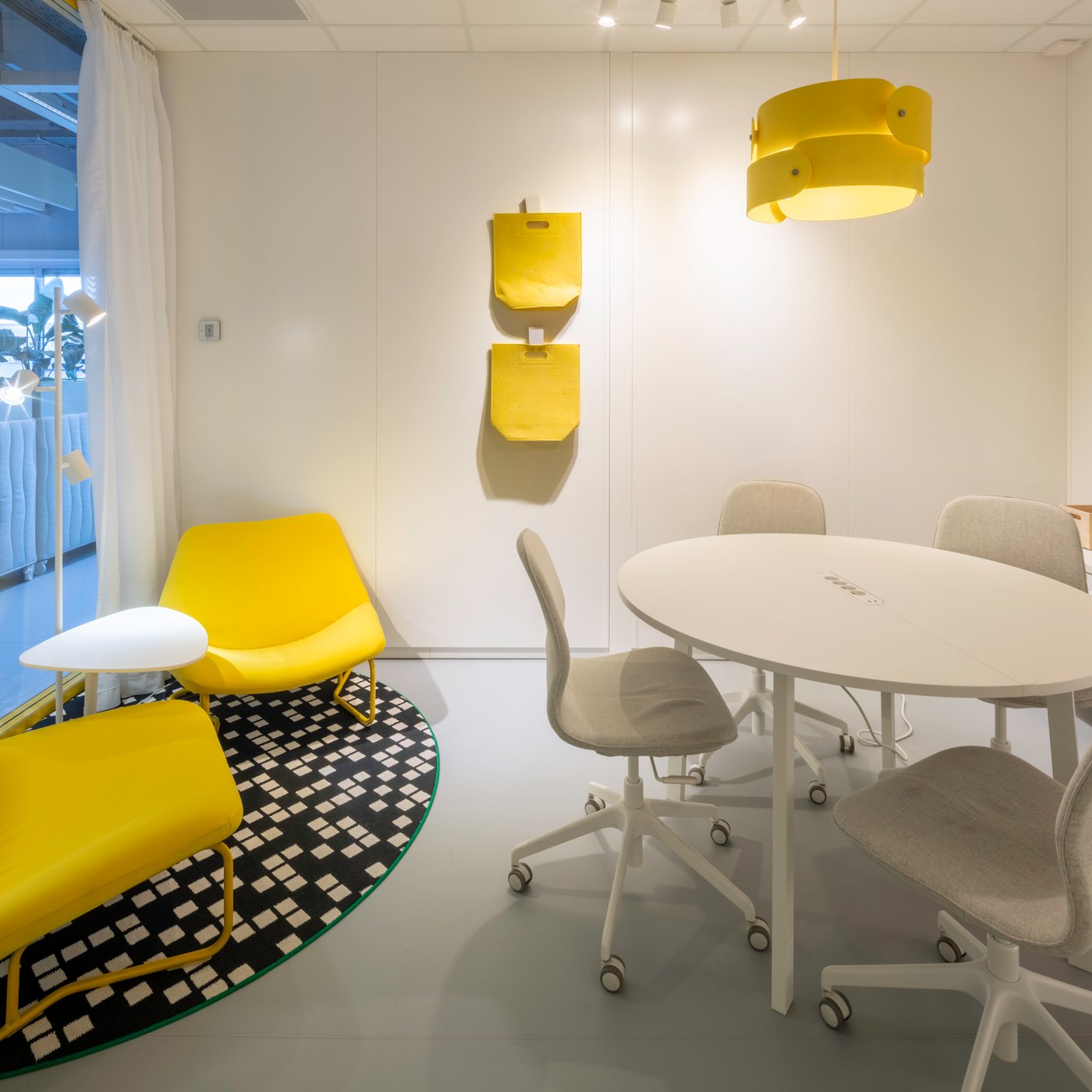 Un coin réunion jaune vif avec des assises IKEA et un éclairage doux crée un endroit stimulant pour des discussions rapides et une collaboration fluide.