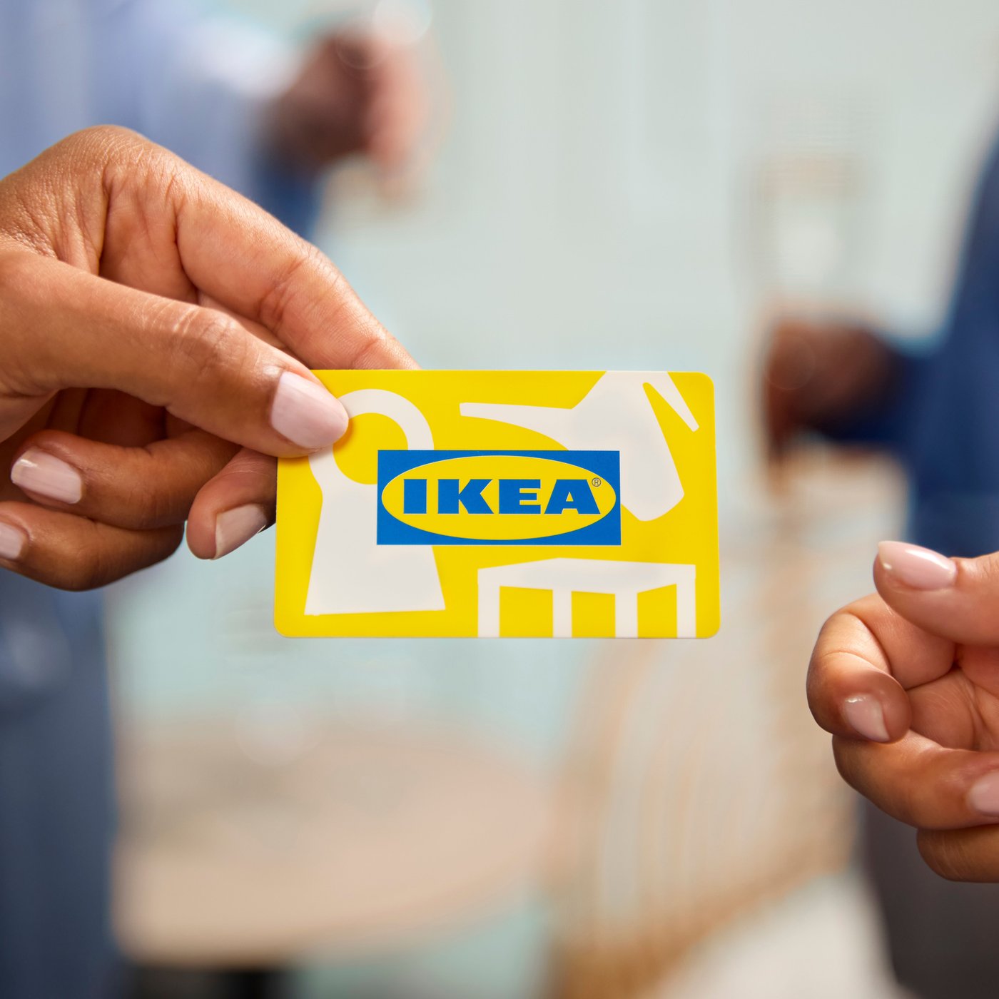 黄色いIKEAギフトカードを手渡ししている