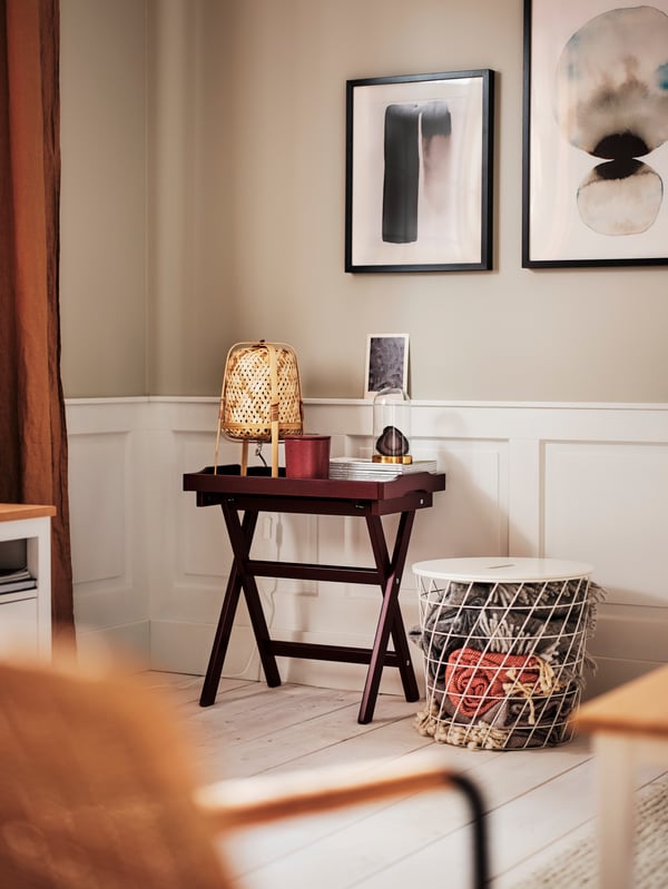 Two posters in black RIBBA frames on a wall above a dark red MARYD tray table and a white KVISTBRO storage table.