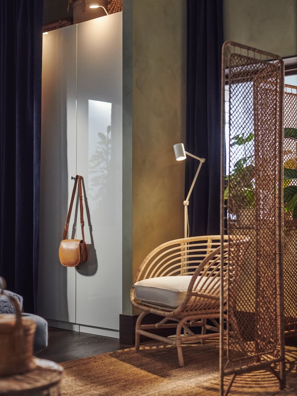 A handmade TOLKNING rattan room divider stands in a hall next to a BUSKBO armchair.
