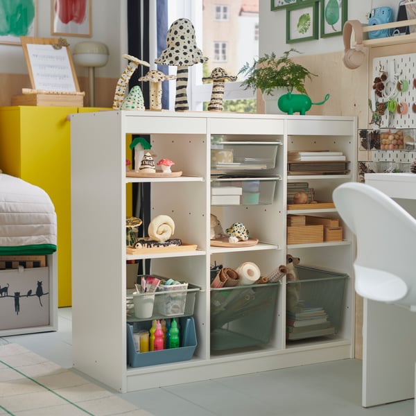 A child’s room features a white TROFAST storage combo filled with hobby supplies and completed craft projects.