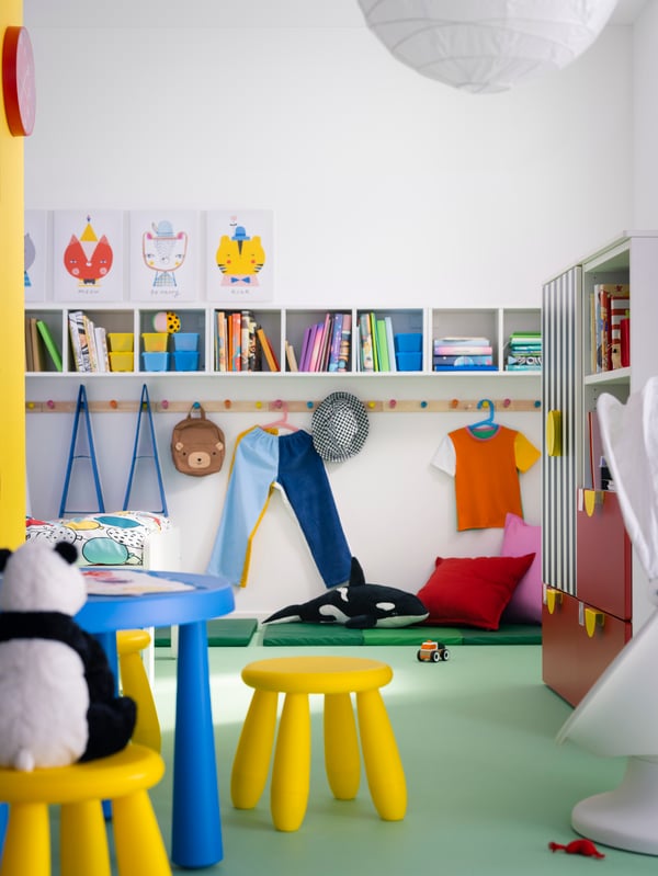 Enkele gele MAMMUT kinderkrukjes voor binnen en buiten staan in een kinderkamer bij een blauwe MAMMUT kindertafel voor binnen en buiten.