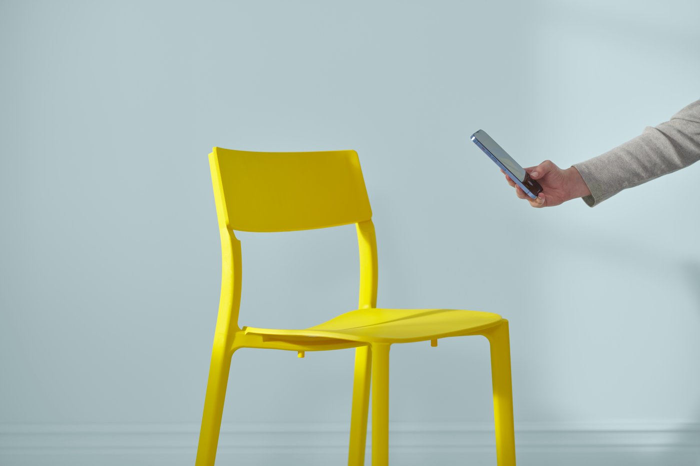 En hand som sträcker ut sig för att ta en bild på en gul IKEA stol.