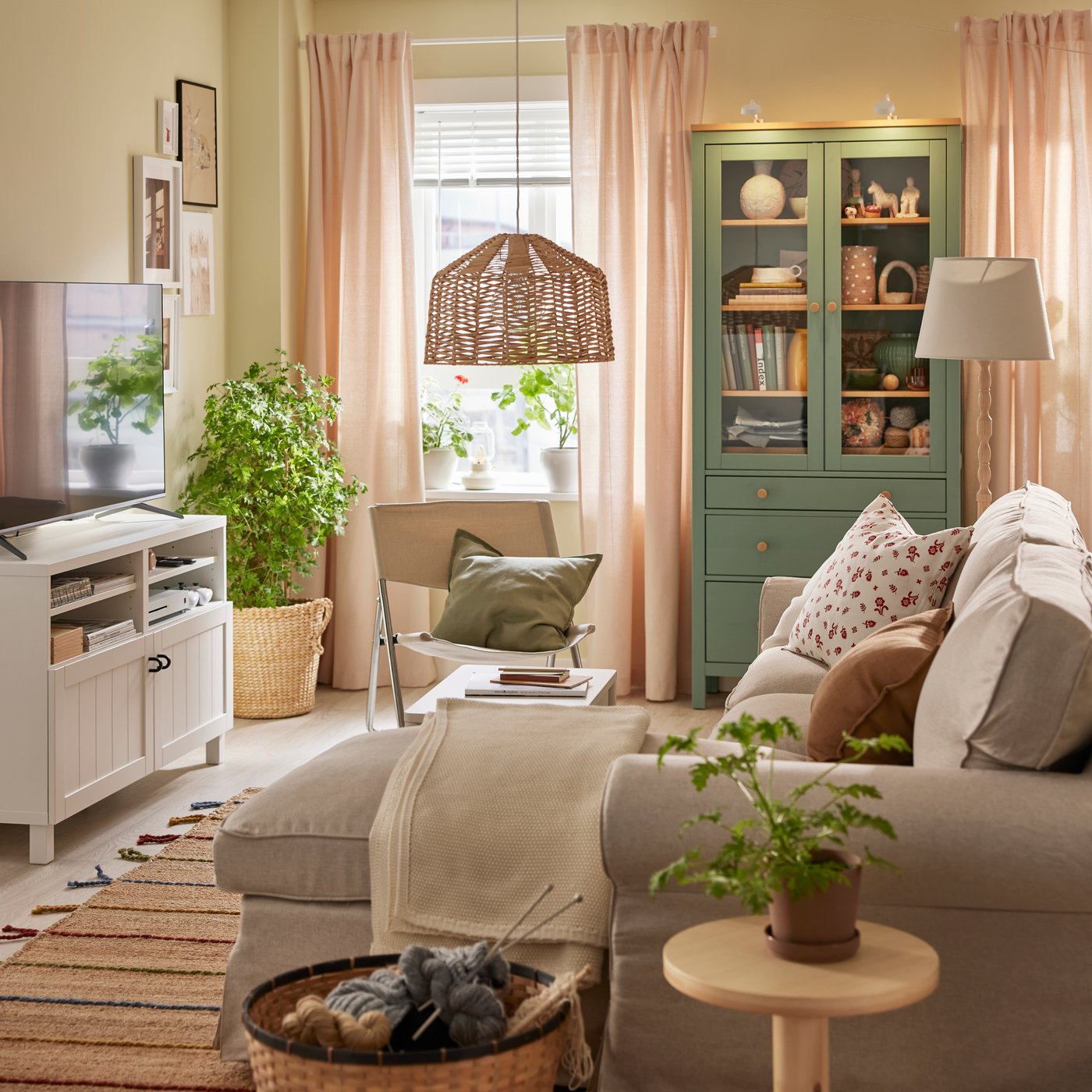 Un divano a 3 posti EKTORP con chaise longue è affiancato da un armadio HEMNES con ante in vetro e da una panca TV BESTÅ con ante.
