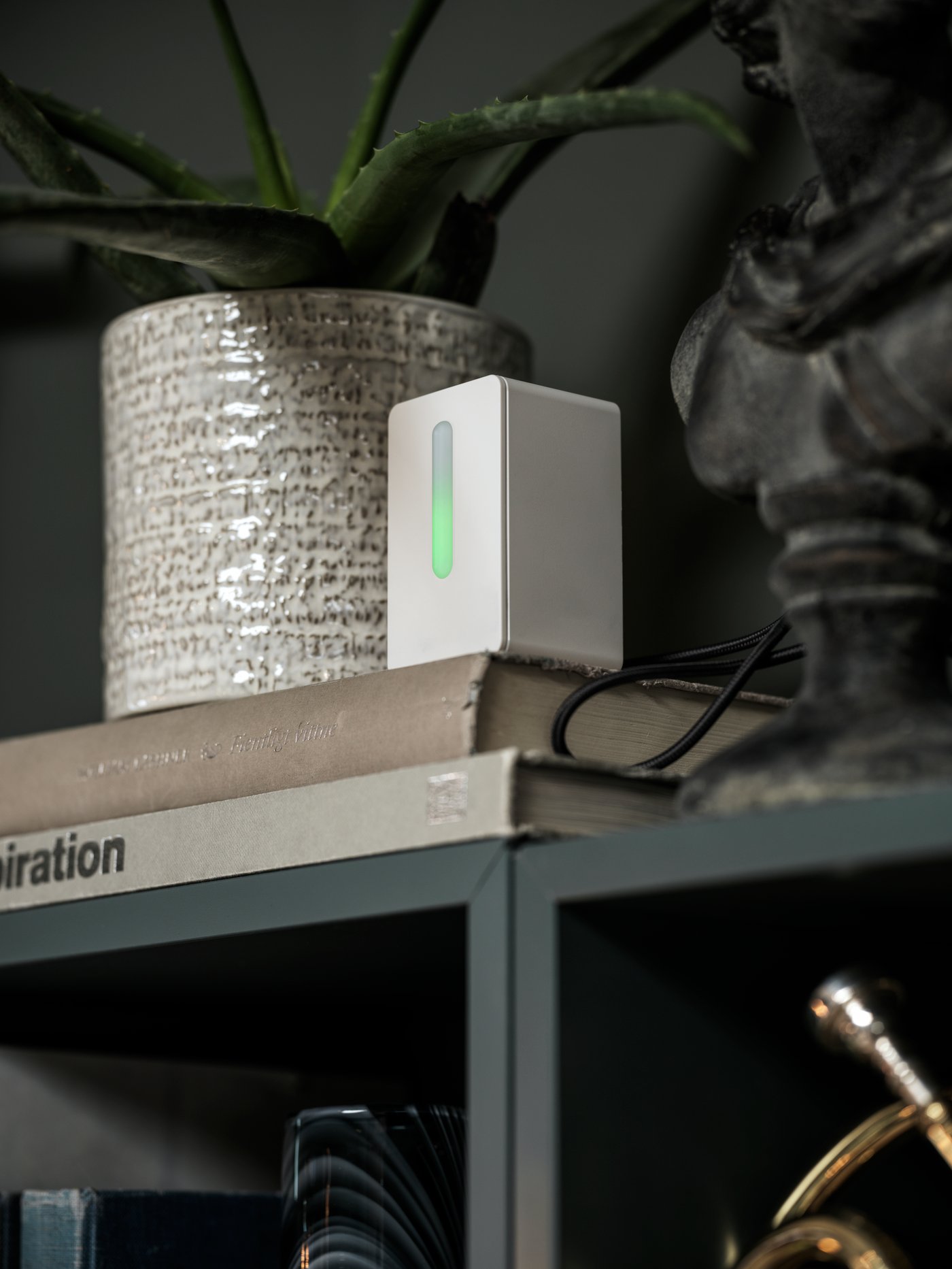 A white VINDRIKTNING air quality sensor stands alongside a white CHIAFRÖN plant pot and decorations on wall-mounted cabinets.