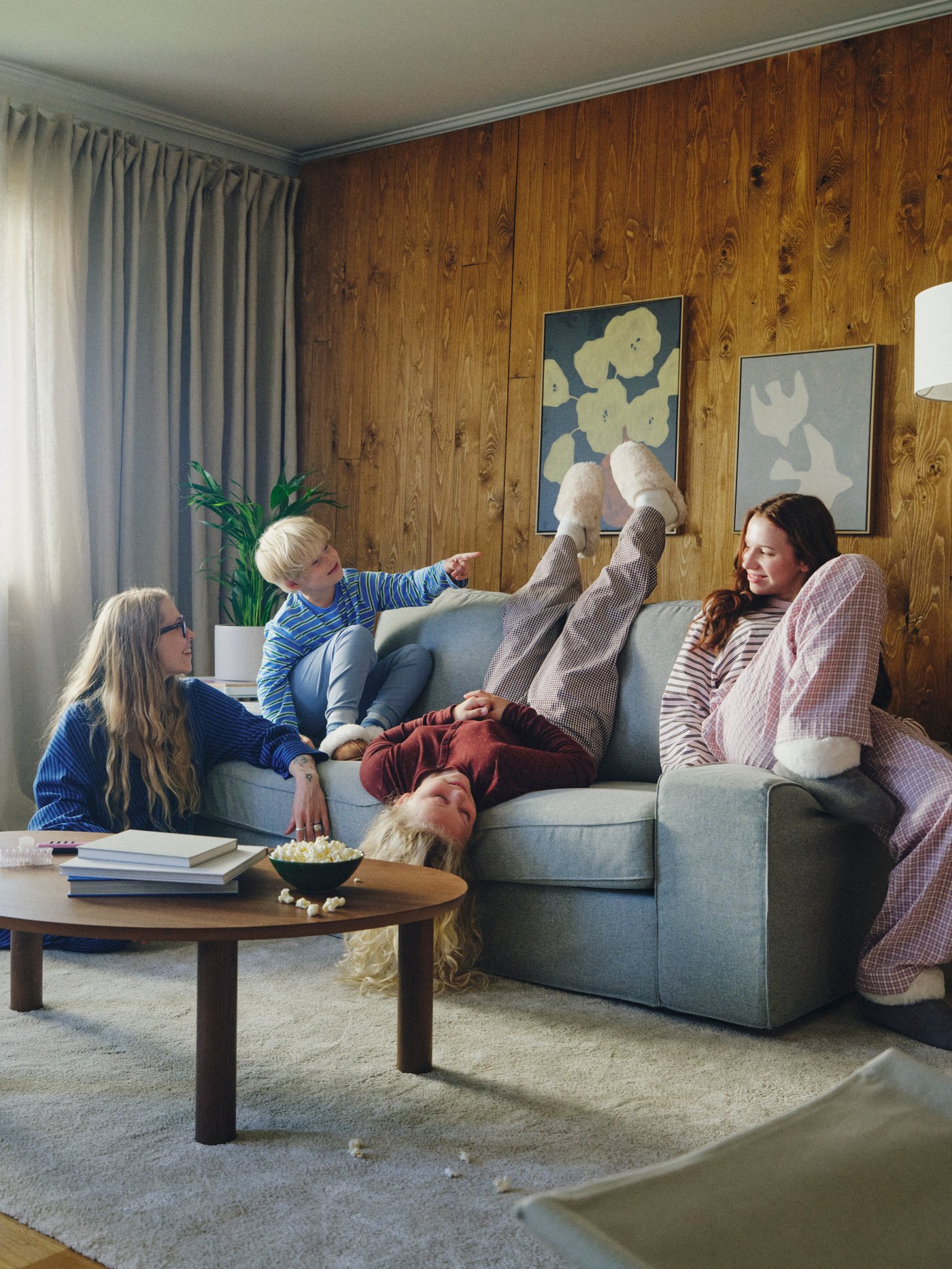 Kolme lasta loikoilee KIVIK-kaksipaikkaisella sohvalla värissä Tibbleby beige/harmaa. Yksi lapsista on ylösalaisin ja kurottelee kohti matalaa pöytää.