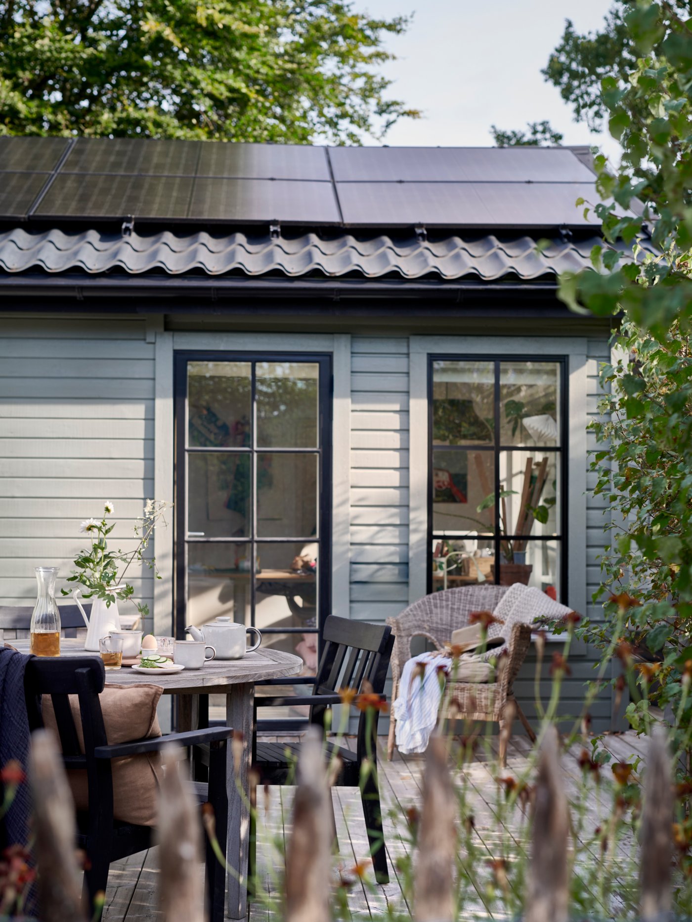 Cabanon ou maison avec des panneaux solaires. Vue extérieure avec une terrasse et des arbres.