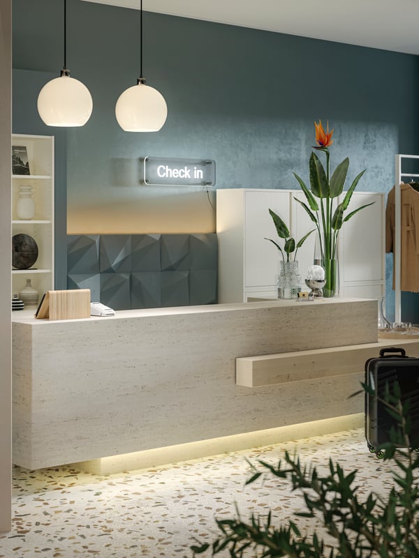 Twee witte glazen/vernikkelde JÄRPLIDEN hanglampen boven een onthaalbalie in beige steenpatroon sieren een moderne hotellobby.