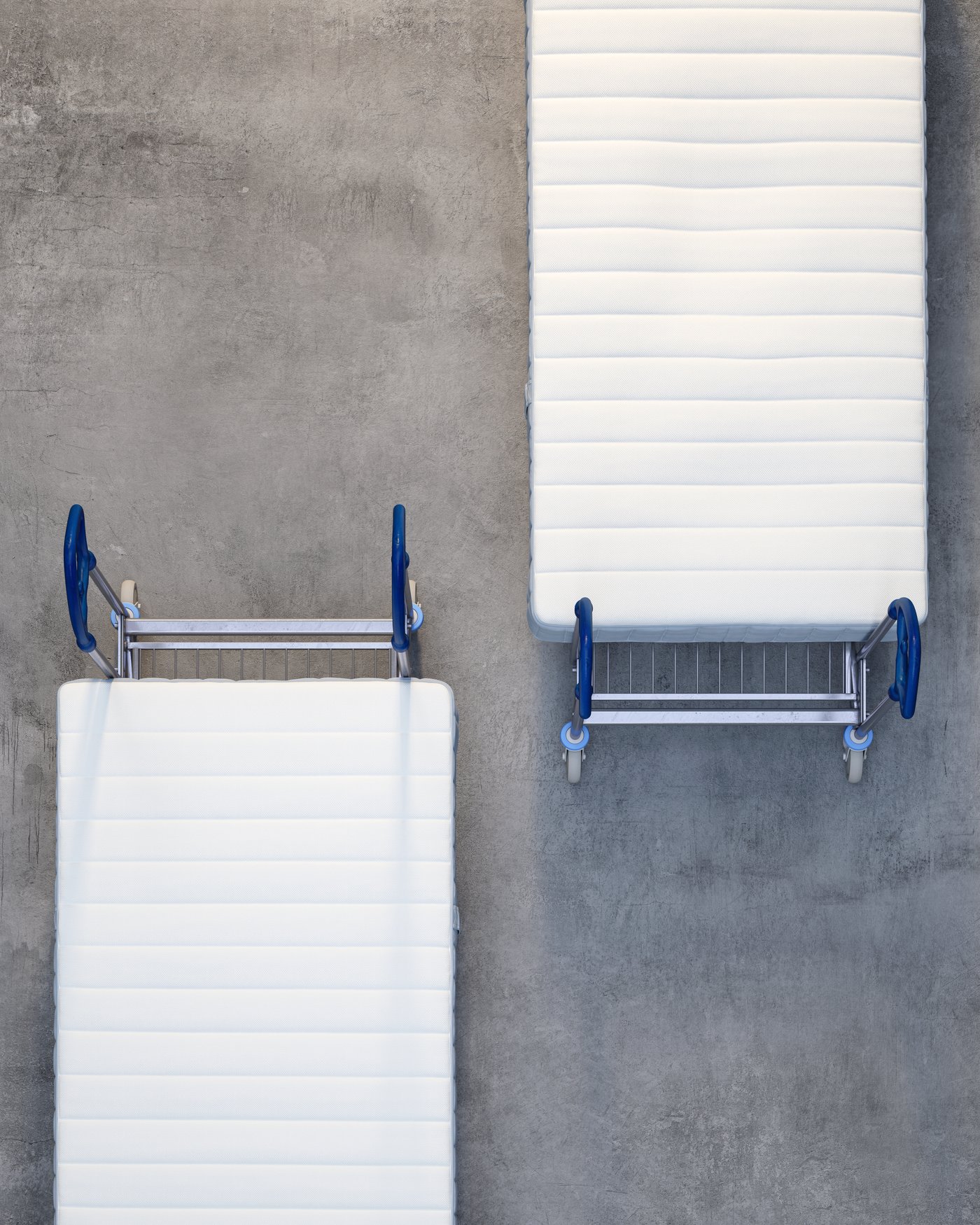 A birds eye view of two mattresses laying on trolleys on a concrete floor.
